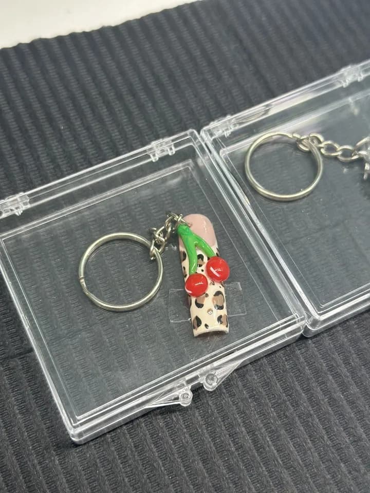 A leopard print nail charm with cherries, on a key ring in a clear case